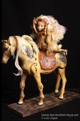 N°100: La jeune cavalière nue
						Création 2026
						Dimensions: 33X30X10 cm. 
						Auteur; Loïc Jugue
						Technique : Jeune poupée nue sur un cheval ayant une selle avec un cœur, tous les deux brûlés. Socle en bois de palette brûlé.
 