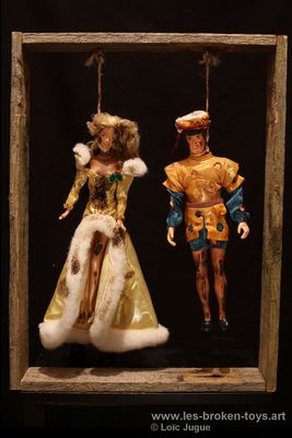 N°76: Vive le roi... Vive la reine!!!, 
						Création 2026, 
						Dimensions: 50X38X18 cm. 
						Auteur; Loïc Jugue
						Technique : Poupée homme et poupée femme type royale, pendues et brûlées, cadre en bois de palette. 