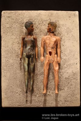 N°83: Tableau de cendre Happy couple
						Création 2026
						Dimensions: 41X33X8 cm. 
						Auteur; Loïc Jugue
						Technique : Poupées (homme,femme) clouées et brûlées sur une toile recouverte de cendre, châssis bois. 